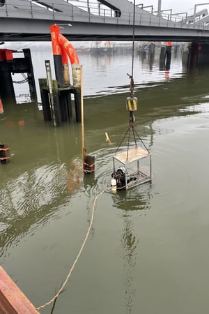 Abgesenkter Taucher im Arbeitskorb führt Unterwasserarbeiten an der ehemaligen Rethebrücke in Hamburg-Wilhelmsburg durch. Rückbau mit Marine-Service und begleitender Kampfmittelsondierung.