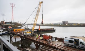 Rückbau der ehemaligen Rethebrücke in Hamburg-Wilhelmsburg: Raupenkran mit Vibrationsramme zieht Stahlpfahl, Team mit Tauchern und Kampfmittelsondierung sichert die Arbeiten vom Wasser aus.