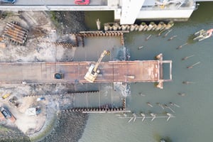 Luftbild vom Rückbau der ehemaligen Rethebrücke in Hamburg-Wilhelmsburg: Bagger auf Arbeitsplattform entfernt Spundwände/Stahleinbauten im Wasser, mit Kampfmittelsondierung und maritimem Rückbau.
