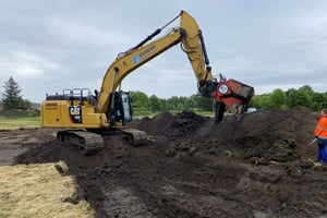 CAT Bagger mit Minebuster-Sieblöffel siebt Material zur Kampfmittelbergung in Leck, Schleswig-Holstein. Einsatz im Rahmen der Kampfmittelsondierung.