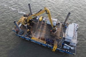 uftaufnahme der EGGERS Jack-Up-Barge mit Langarmbagger und Bohrplatz. Marine Service führt Kampfmittelsondierung und Arbeiten für das LNG-Projekt in Wilhelmshaven/Nordsee durch.