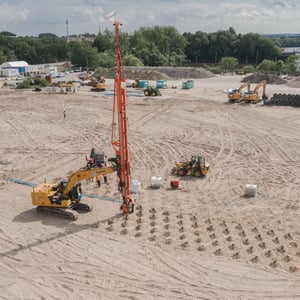 CAT Bagger mit Bohrlafette der EGGERS Kampfmittelbergung bei der Kampfmittelsondierung auf einer Baustelle in Hamburg, weitere Baumaschinen und Bagger im Hintergrund.