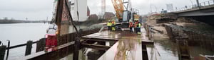 EGGERS Wasserbau – Team bei Arbeiten an Spundwänden mit Kran und Schweißarbeiten am Flussufer in Deutschland