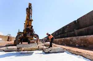 Bagger mit Greifer hebt Betonteile zur Bombenräumung in Helgoland