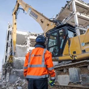 EGGERS Abbruch Hamburg – Bagger im Rückbau eines Gebäudes mit Mitarbeiter auf der Baustelle